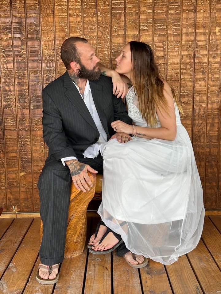 A bride and groom sitting on a wooden bench